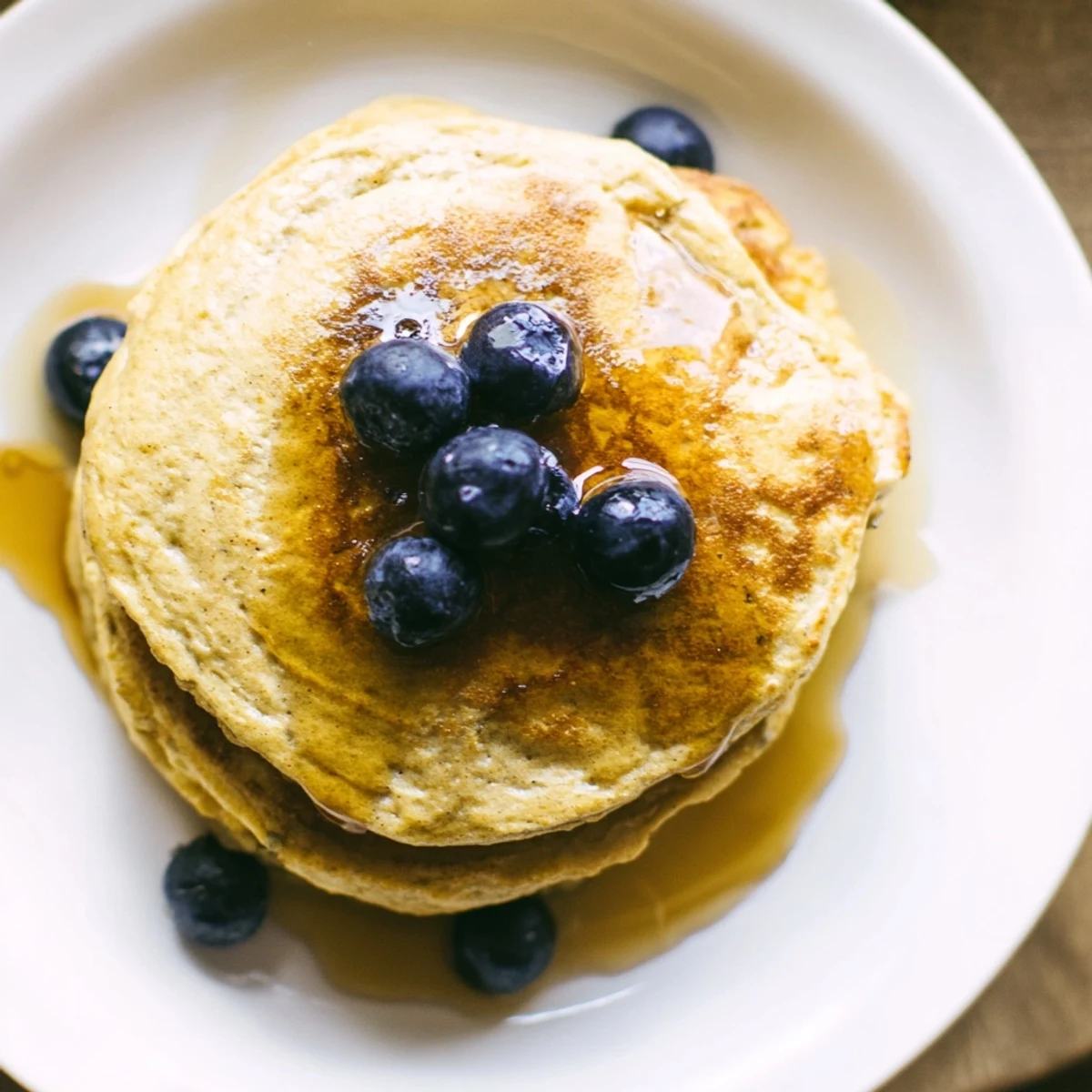 A stack of homemade Protein Banana Pancakes, drizzled with syrup– imagine the delicious aroma!