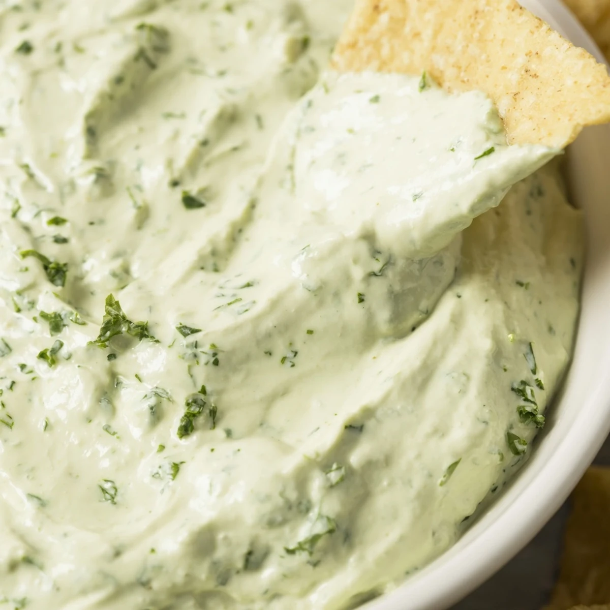 Green Goddess Salad Dip served in a rustic bowl surrounded by colorful crunchy veggies like carrot sticks and cucumber slices.