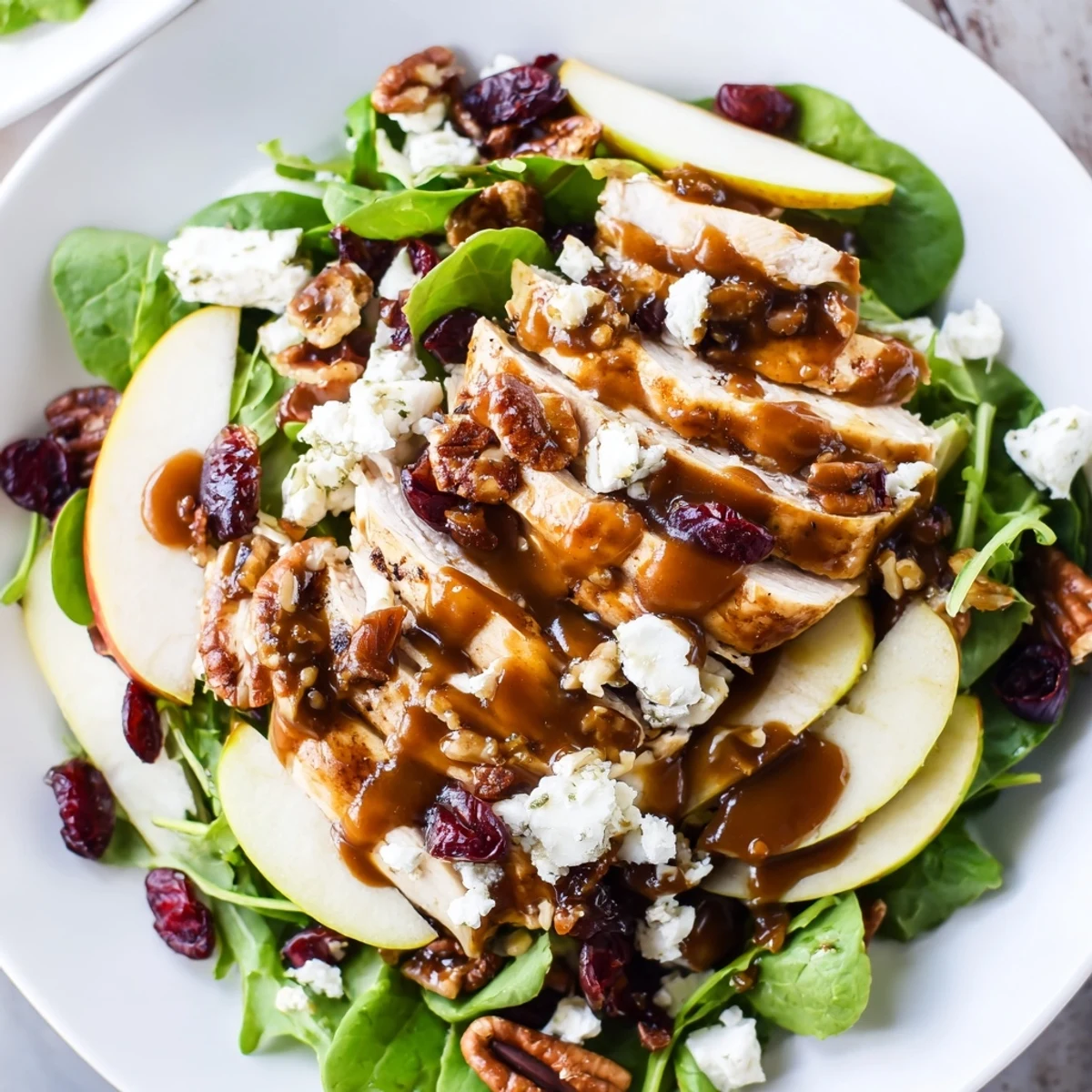 Platter of caramel apple chicken salad with mixed greens, sliced apples, and a drizzle of caramel-pecan dressing.