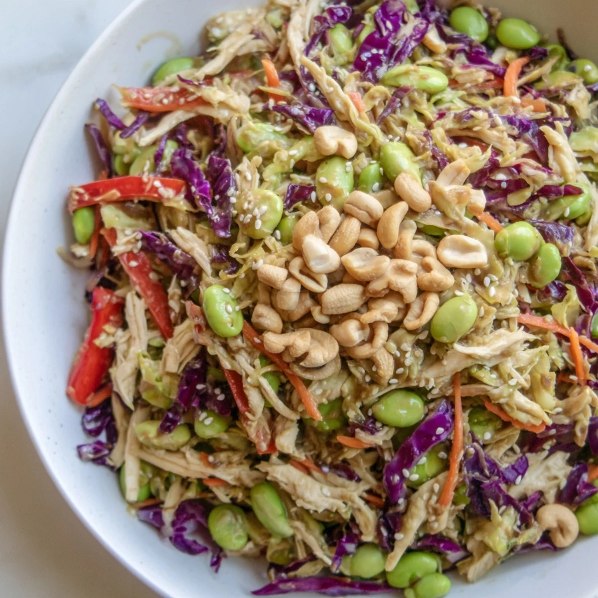 Serving suggestion for Edamame Crunch Chicken Salad plated alongside a glass of iced green tea, featuring a colorful mix of edamame and fresh vegetables.