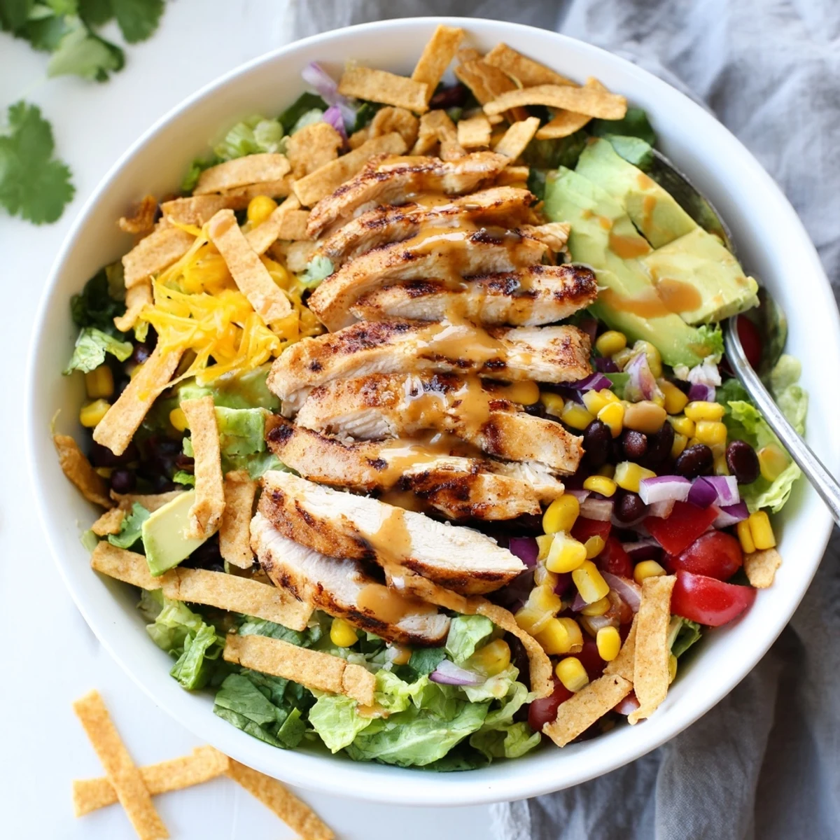 Freshly tossed Honey Lime Chicken Taco Salad with honey-lime dressing, cherry tomatoes, red onion, and golden chicken slices on a bed of romaine.