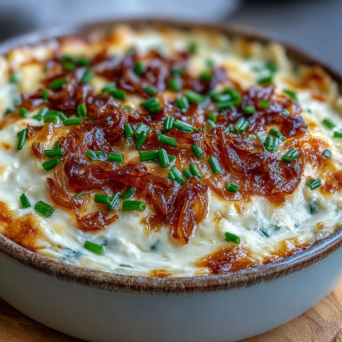 Cheesy Smoked Gouda & Onion Dip with a golden crust and chopped chives garnish in a rustic serving dish.