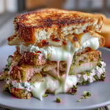 Two halves of a warm Goat Cheese Grilled Cheese with Honey & Chili Flakes reveal melted chèvre, cream cheese, and sweet honey. 
