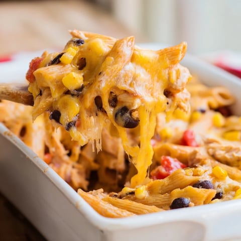 Golden, bubbly Monterey Jack and cheddar cheese melts over a Tex-Mex Chicken Burrito Pasta Bake served in a white dish.