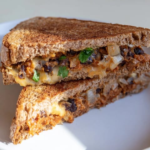 A close-up of a perfectly toasted Black Bean Grilled Cheese, oozing melted cheese and savory beans.