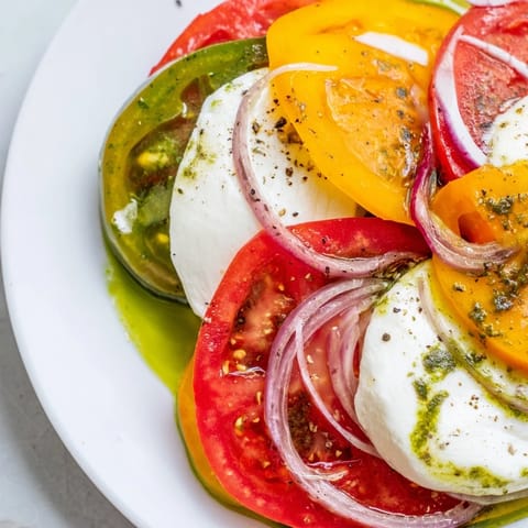 Summer tomato salad glistening with basil oil, featuring colorful tomatoes and fresh mozzarella.