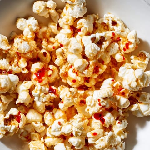 A close-up of freshly made hot honey butter popcorn, drizzled with sweet and savory sauce.