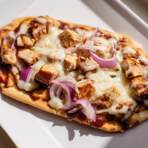Sizzling BBQ Chicken Flatbread just pulled from the oven, drizzled with extra tangy sauce.  