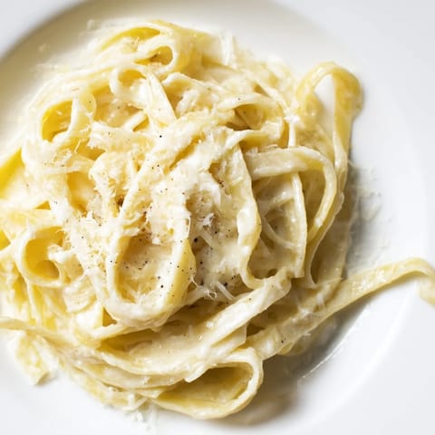 A comforting bowl of roasted garlic cream pasta tossed with al dente fettuccine, finished with a drizzle of olive oil and black pepper.