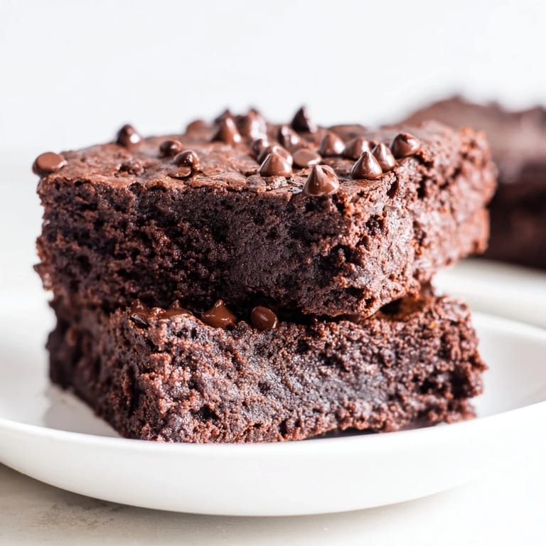 A warm, freshly baked pan of Greek yogurt brownies, revealing a moist interior, perfect for a treat.