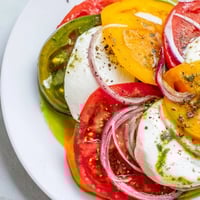 Summer tomato salad glistening with basil oil, featuring colorful tomatoes and fresh mozzarella.